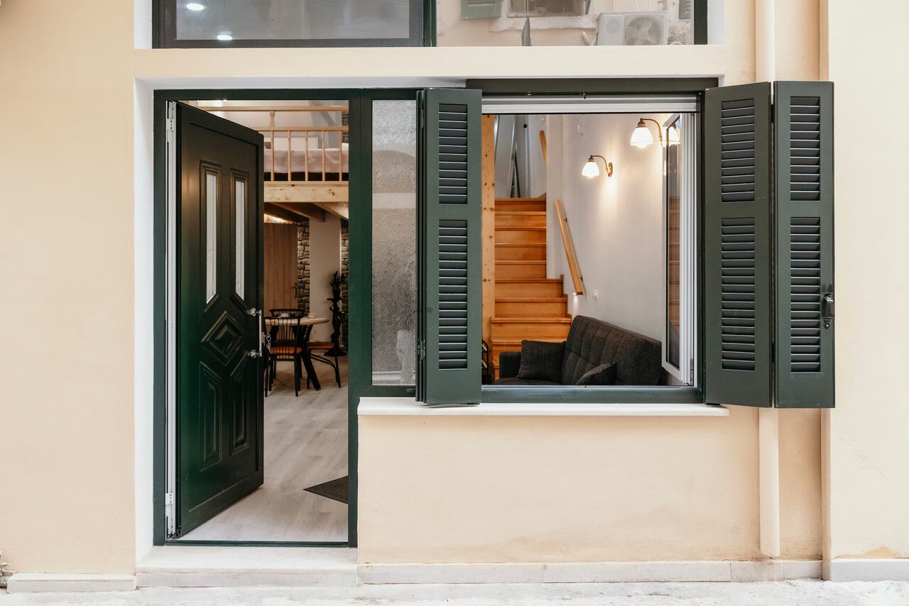 The green door and open shuttered window of Casa Paseo, seen from the alley in Corfu Old Town.